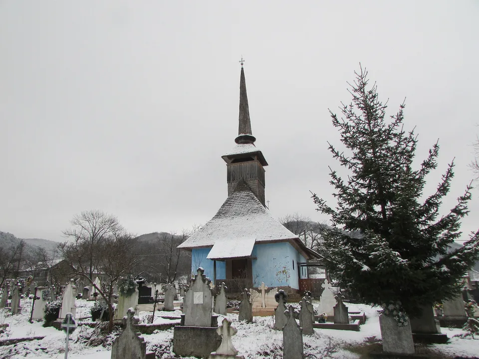 Snow-covered wooden church and cemetery in Transylvania.